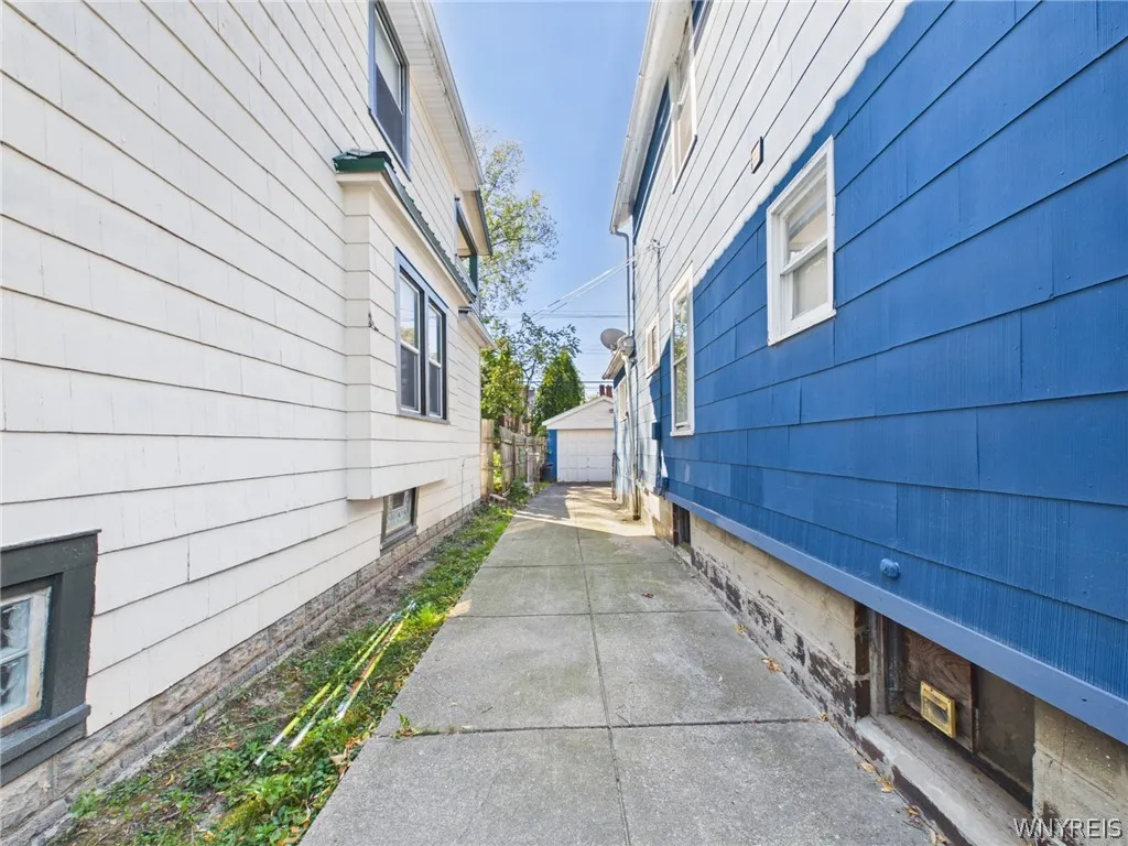 A long concrete driveway runs along the side of the house to the detached garage at the back.