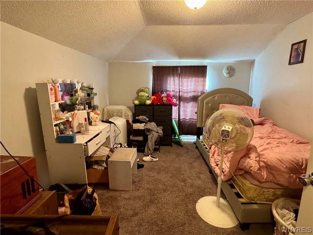 A spacious bedroom features wall-to-wall carpeting and sloped ceilings with integrated lighting.
