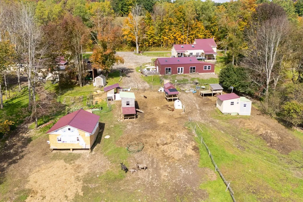 Several outbuildings and fenced pastures dot this sprawling rural property surrounded by mature trees.