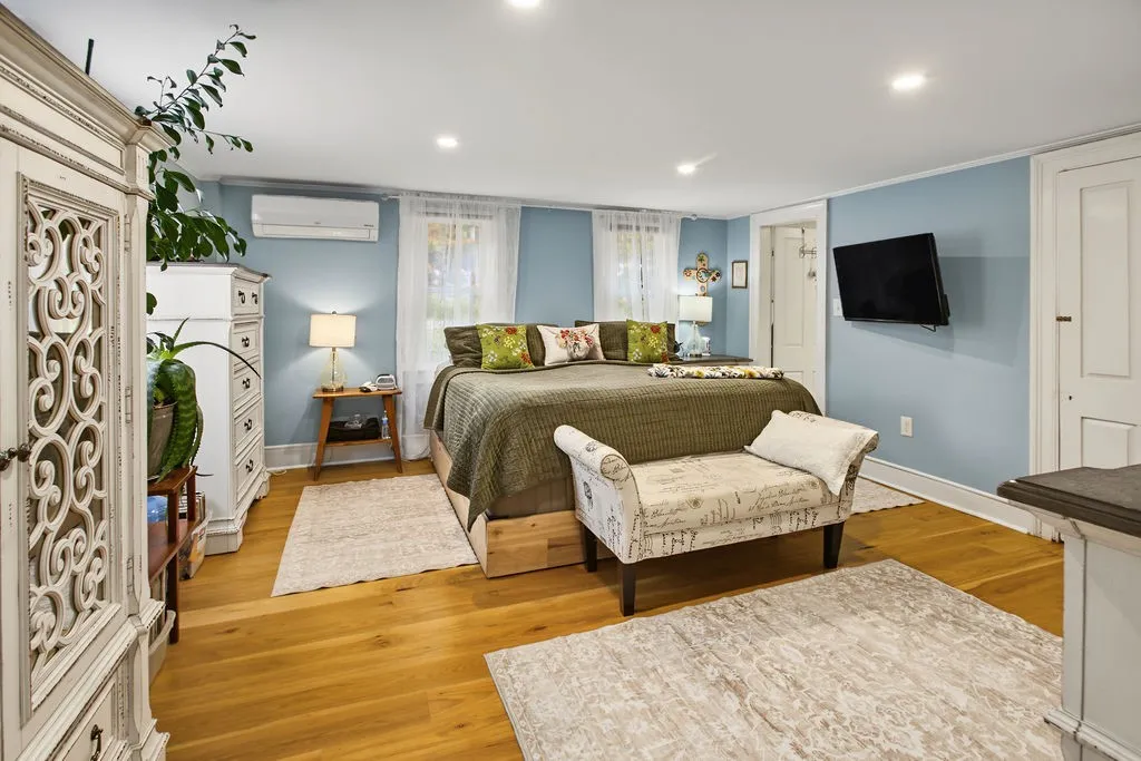 Rich hardwood floors and classic crown molding elevate this serene bedroom retreat.