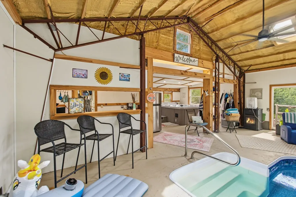Rustic exposed trusses rise above a multi-level indoor recreation space featuring a sparkling in-ground pool.