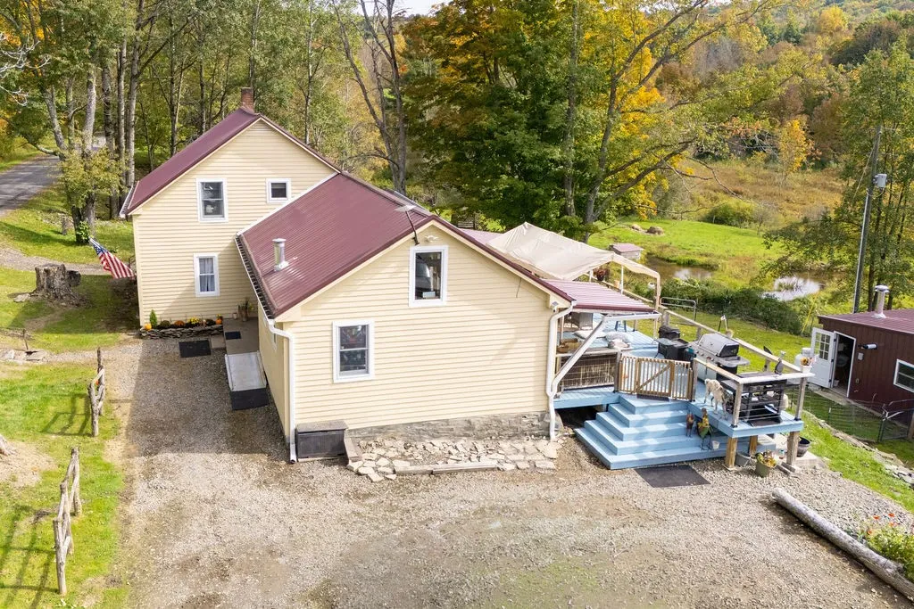 An elevated perspective showcases the multi-level metal roofline and sprawling backyard wood deck.
