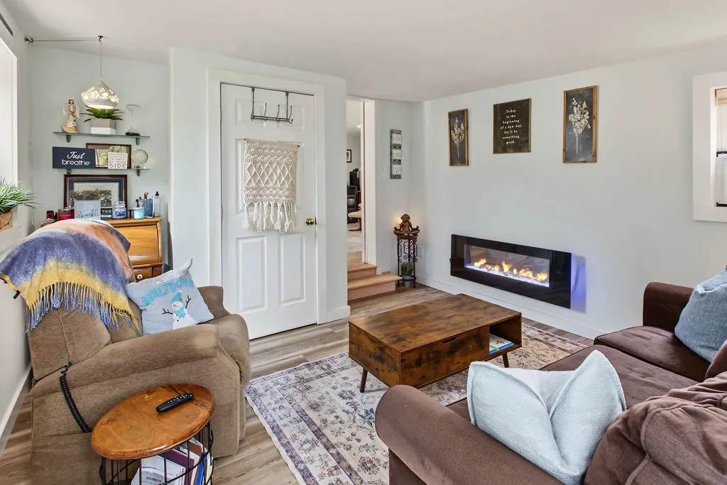 A modern wall-mounted fireplace adds architectural interest to this cozy living space with wood flooring.