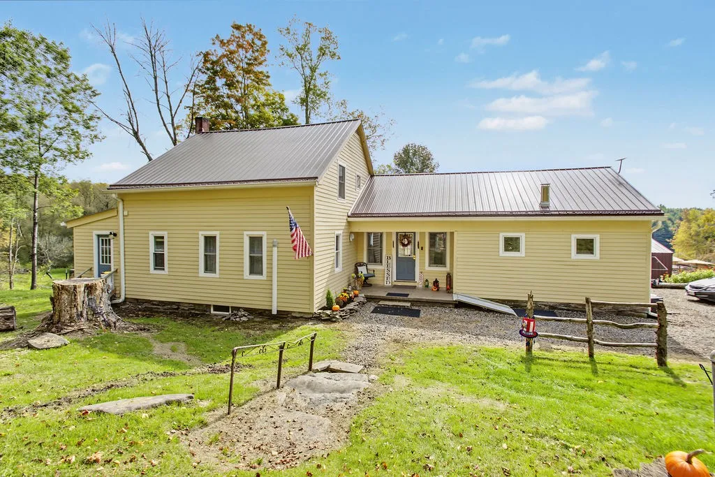 Metal roofing and classic siding define this charming country home set against a wooded backdrop.