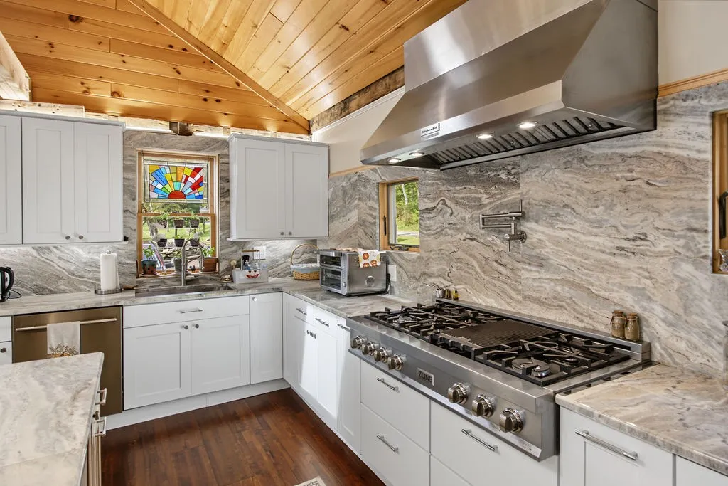Rich wood ceilings and striking stone backsplashes frame this well-appointed gourmet kitchen.