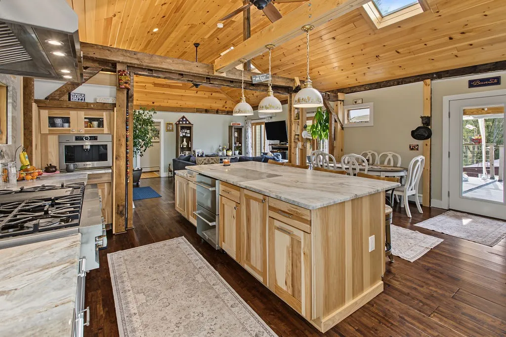 Gleaming hardwood floors and natural wood ceilings enhance this inviting open-concept kitchen space.