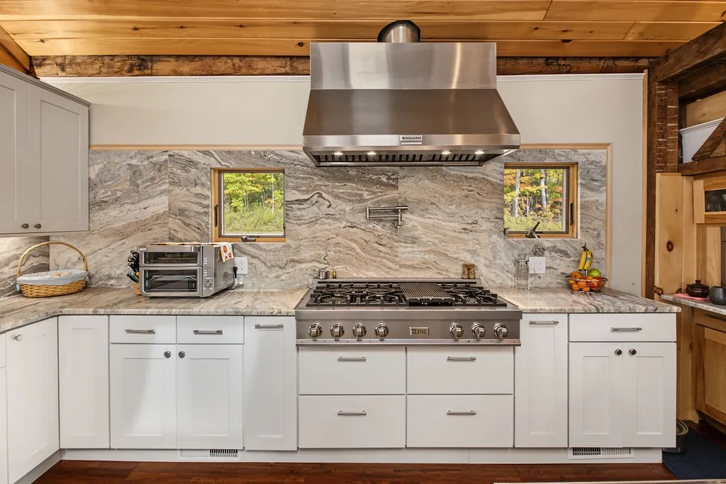 Natural stone surfaces and warm wood ceilings frame this gourmet cooking space.