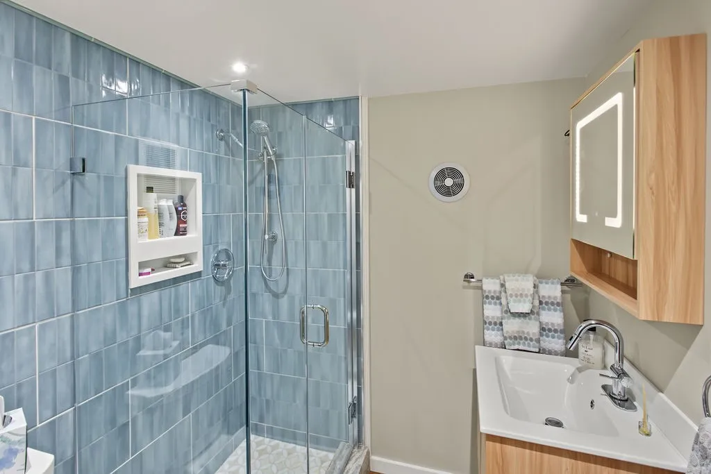 A contemporary glass-enclosed shower highlights tiled walls alongside a modern vanity station.