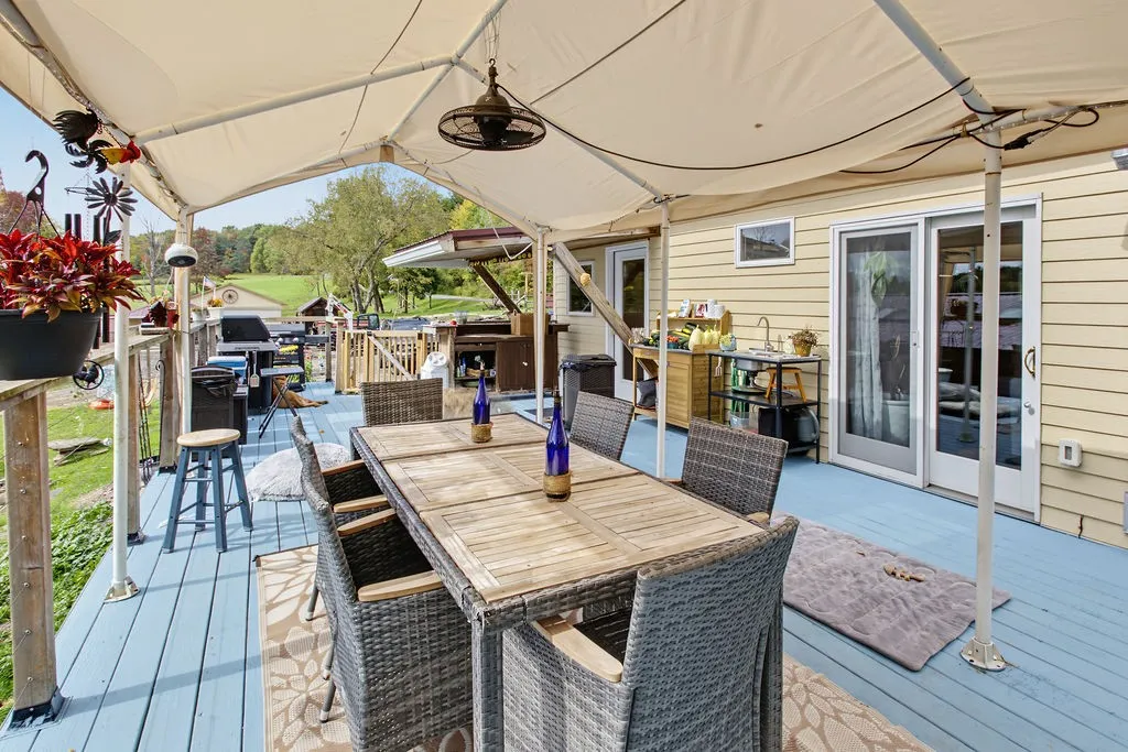 An elevated wood deck with a shaded canopy provides a comfortable outdoor dining area.