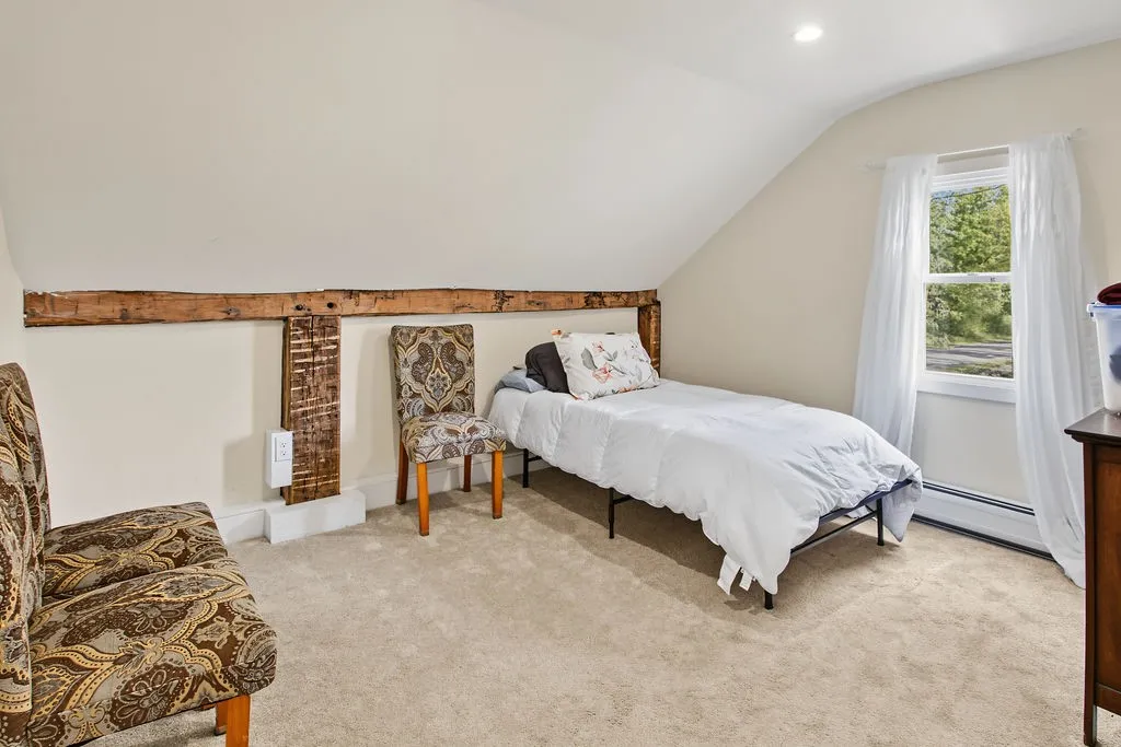 Slanted ceilings and exposed timber beams add rustic character to this cozy upper-level bedroom.