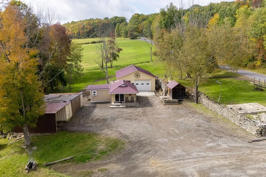 Nestled among mature trees, this countryside property features multiple functional outbuildings and rolling green hills.