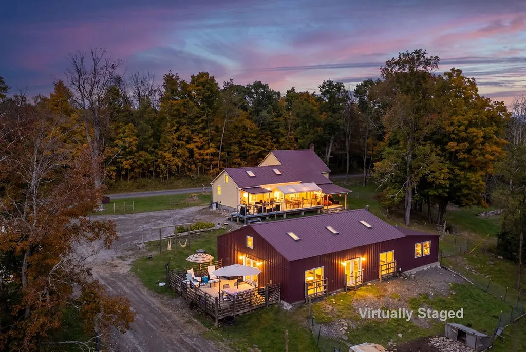 A metal-roofed country estate sits nestled among mature trees against a colorful twilight sky.