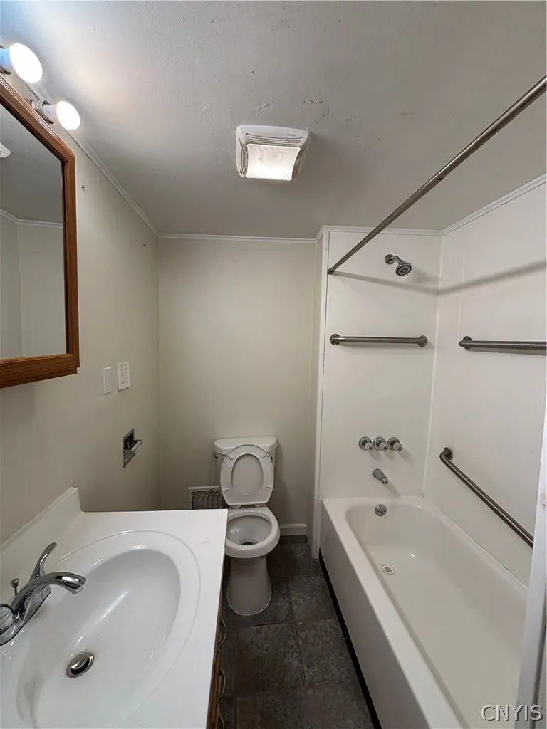 Functional bathroom layout features a tub and shower combination with safety handrails.