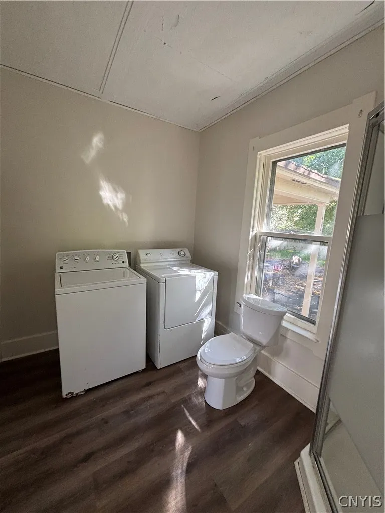 A window brings natural light into this functional laundry space with wood-style flooring.