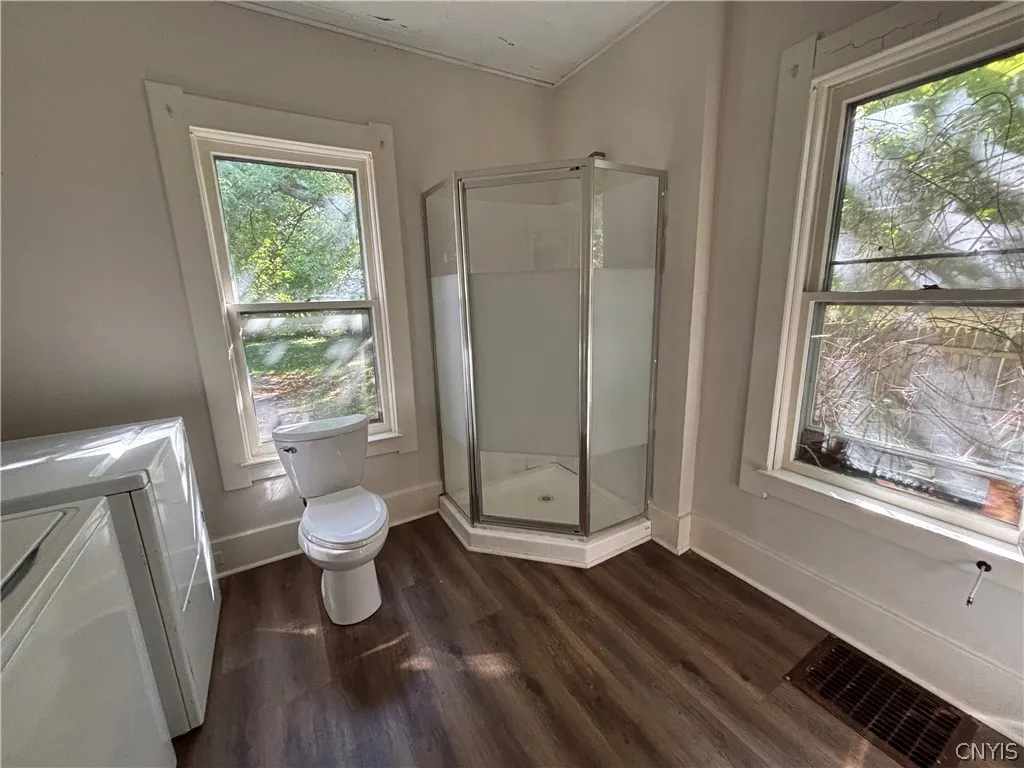 Hardwood floors and natural light from large windows elevate this functional bathroom space.