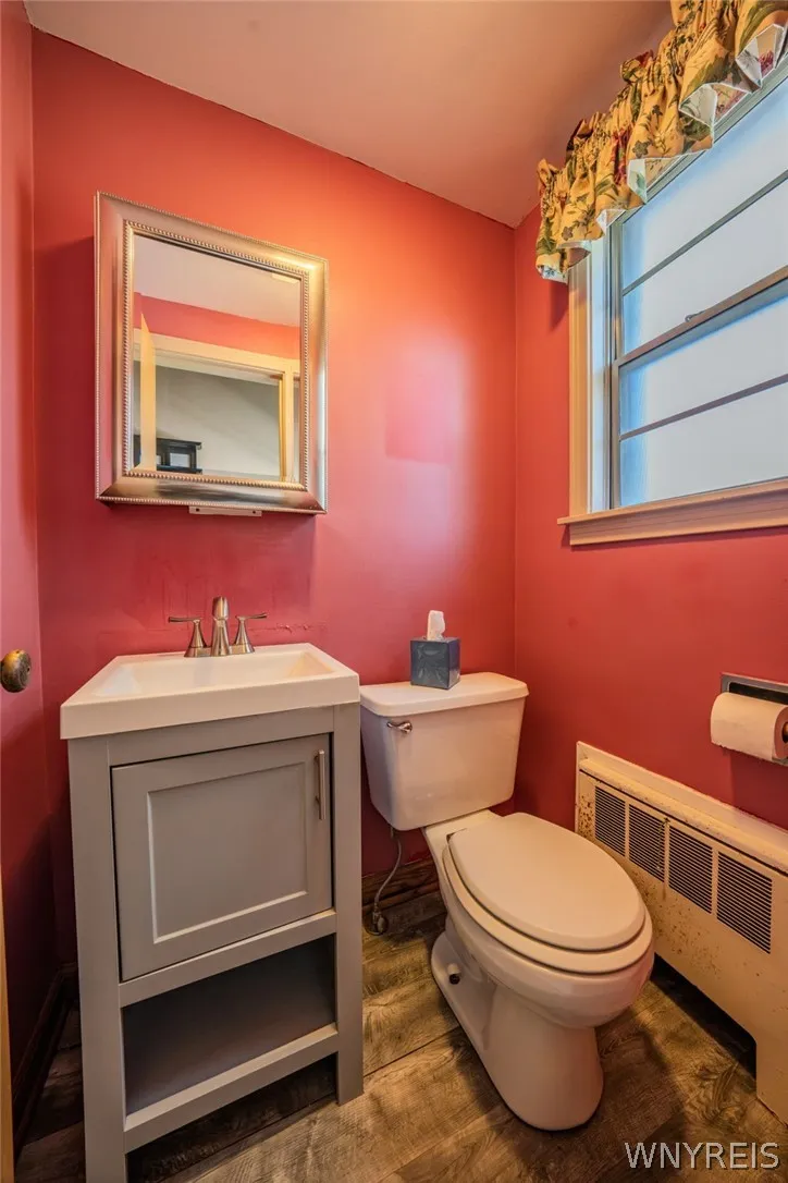 Wood-look flooring complements the half bath & compact vanity and classic fixtures in this cozy powder room.