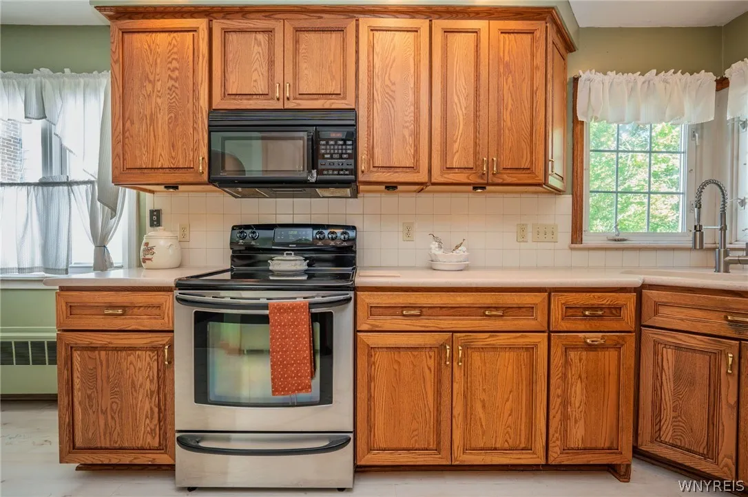 Rich wood cabinetry surrounds integrated stainless steel appliances under bright window light.