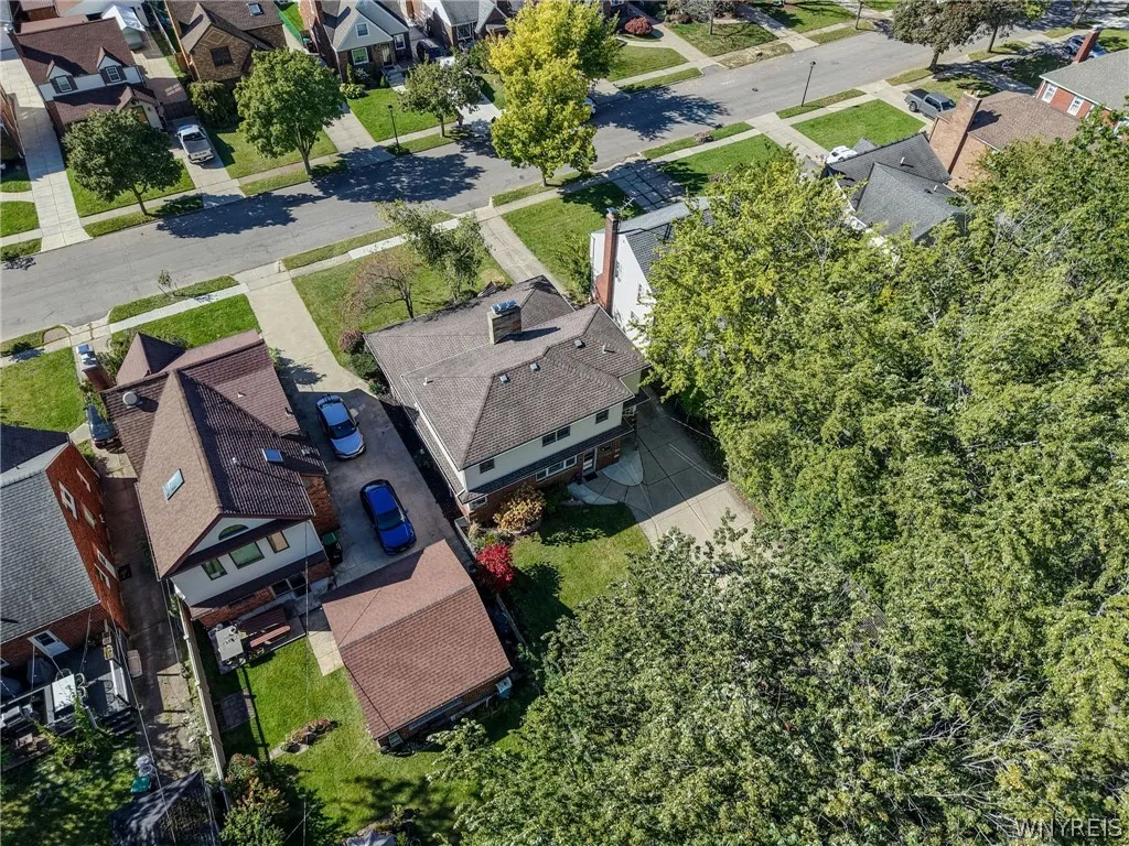An aerial perspective shows the home nestled in a leafy neighborhood with mature trees.