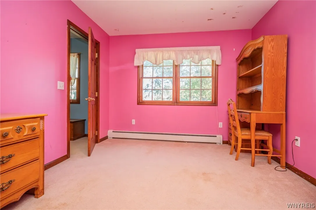A spacious bedroom features classic wood trim, carpet flooring, and a large multi-lite window.