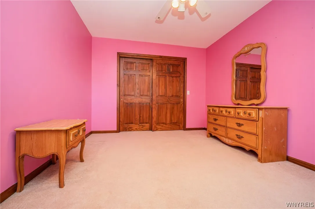 Rich wood closet doors and soft wall-to-wall carpeting define this comfortable bedroom space.