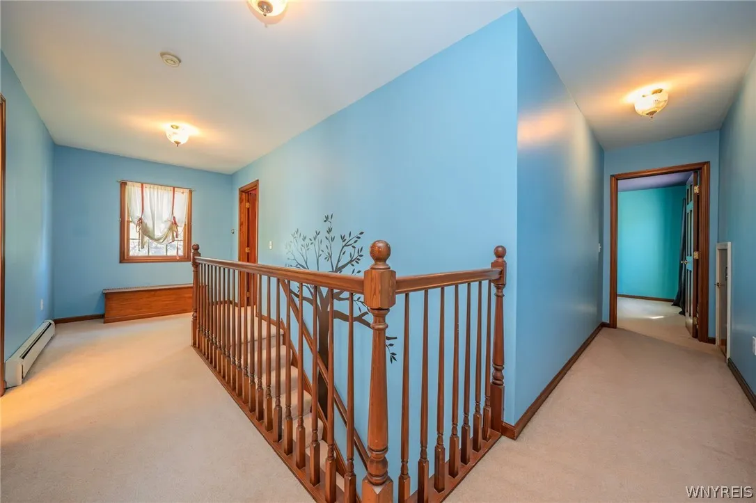 An upper landing features neutral carpeting and a classic wooden balustrade surrounding the staircase.