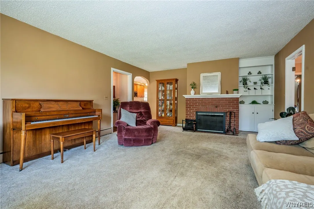 Plush carpeting and a classic brick fireplace anchor this welcoming interior space.