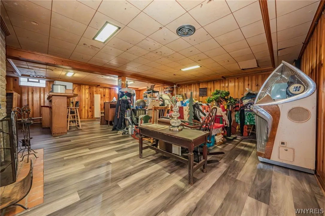 Rich wood-paneled walls and durable plank flooring define this versatile lower-level recreation space. items are for yard/estate sale