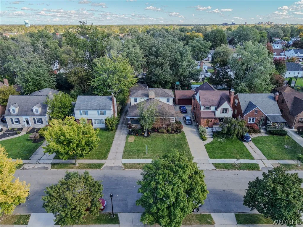 Mature trees shade established lawns along a quiet residential street with paved driveways.