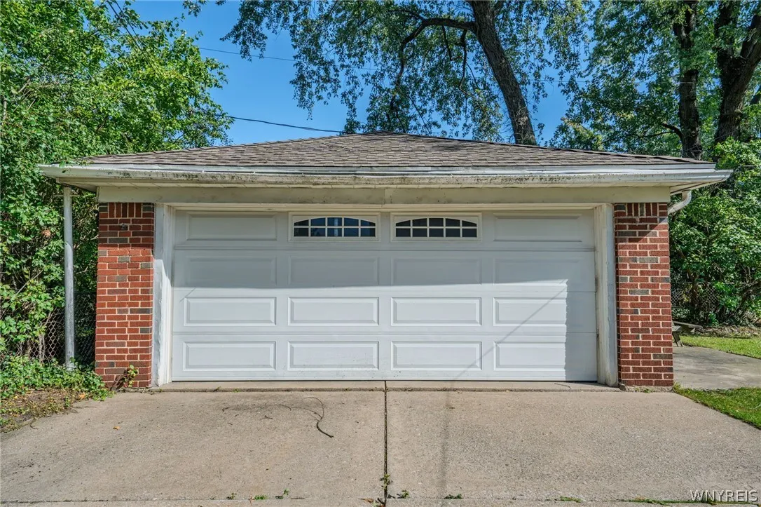 A detached two-car garage features a durable concrete driveway and classic brick accent pillars.