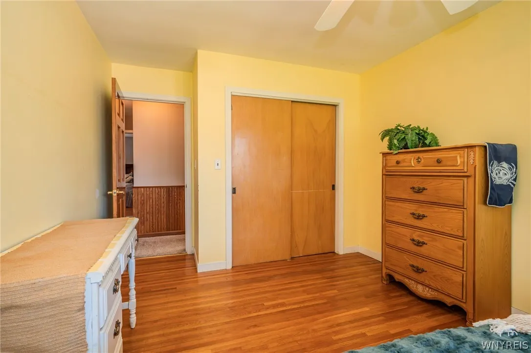 Rich hardwood flooring anchors this versatile bedroom equipped with a classic sliding closet door.
