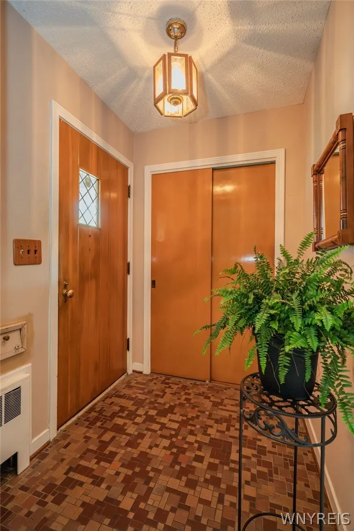 A welcoming entryway showcases patterned tile flooring, a solid wood door, and a spacious closet.