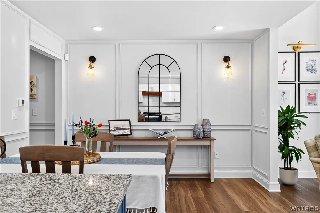 Rich wood flooring pairs with classic wall paneling and elegant recessed lighting.