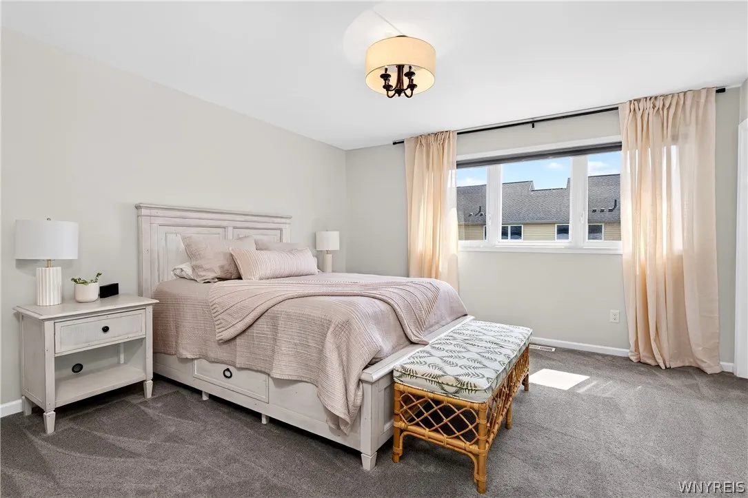 Plush carpeting anchors this peaceful retreat illuminated by natural light from wide windows.