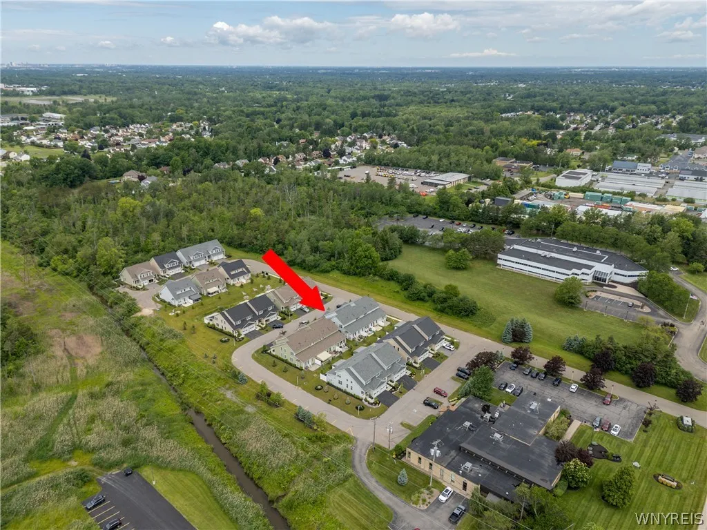 An aerial perspective reveals the residential neighborhood surrounded by dense green forestry.