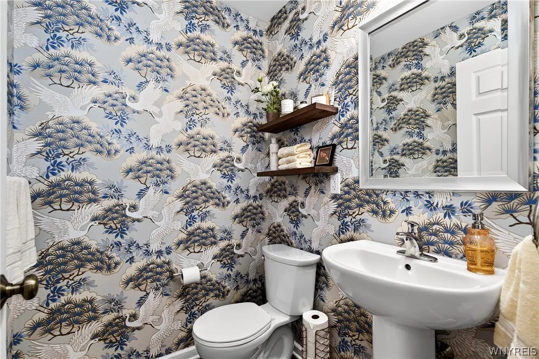 A stylish powder room showcases custom wall covering paired with a classic pedestal sink.