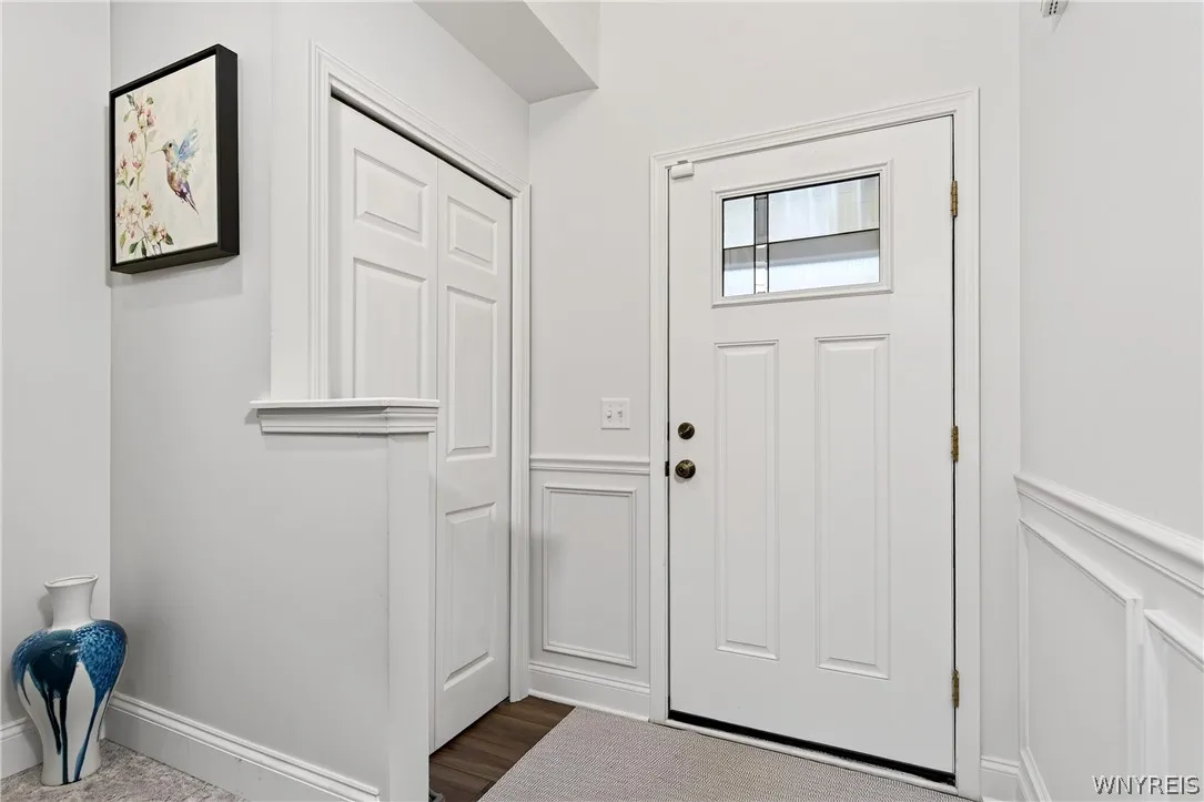 Crisp white wainscoting and a classic panel door define this welcoming entryway.