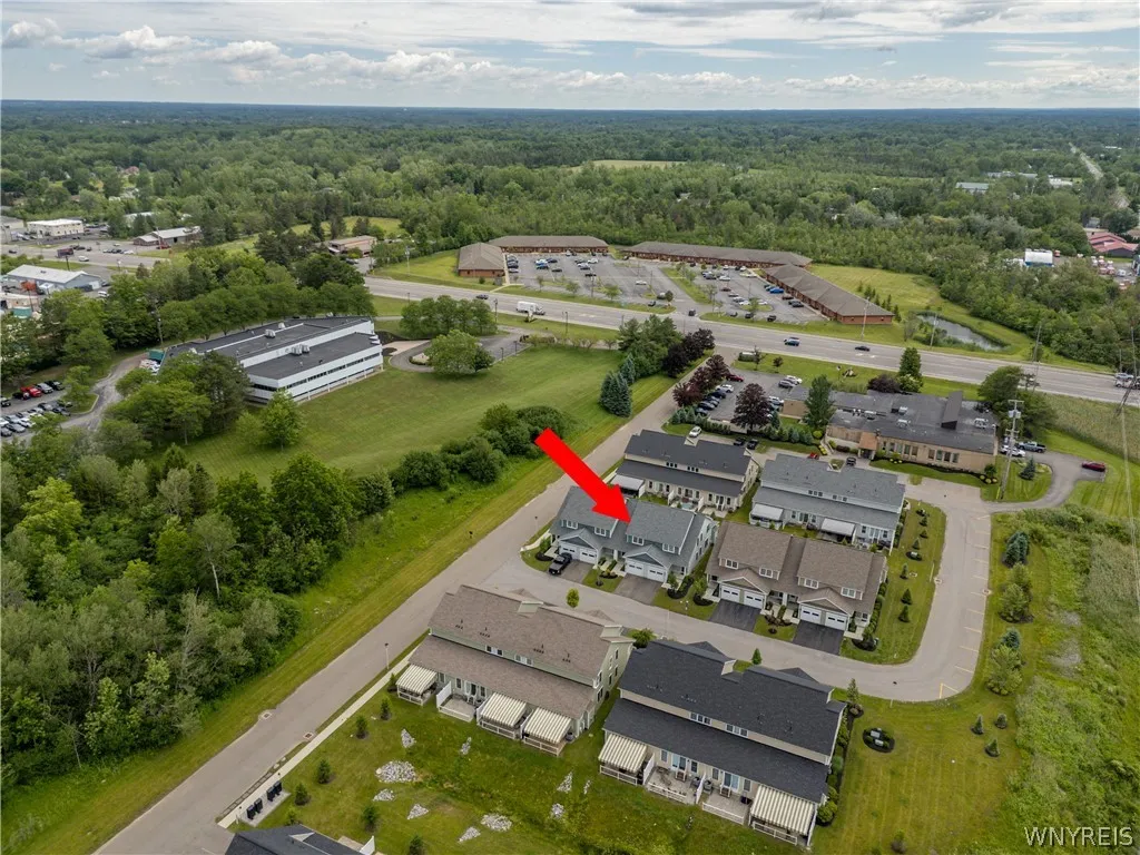 An aerial perspective shows the residential townhome neighborhood surrounded by mature trees.