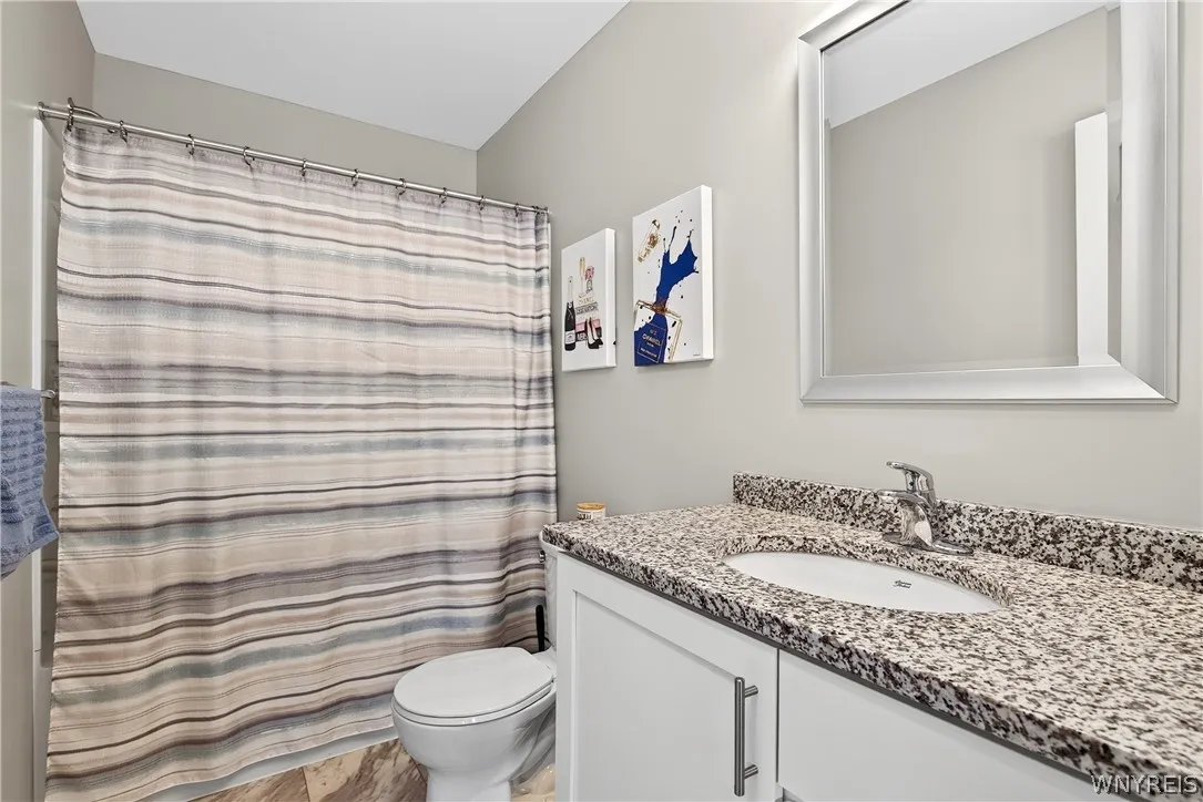 Polished granite countertops complement the clean cabinetry in this updated secondary bathroom.