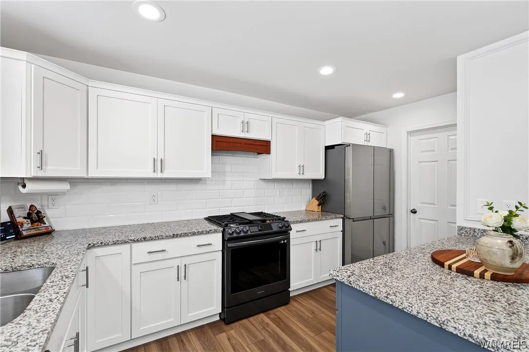 Polished granite countertops complement classic white cabinetry and rich wood floors in this modern culinary space.