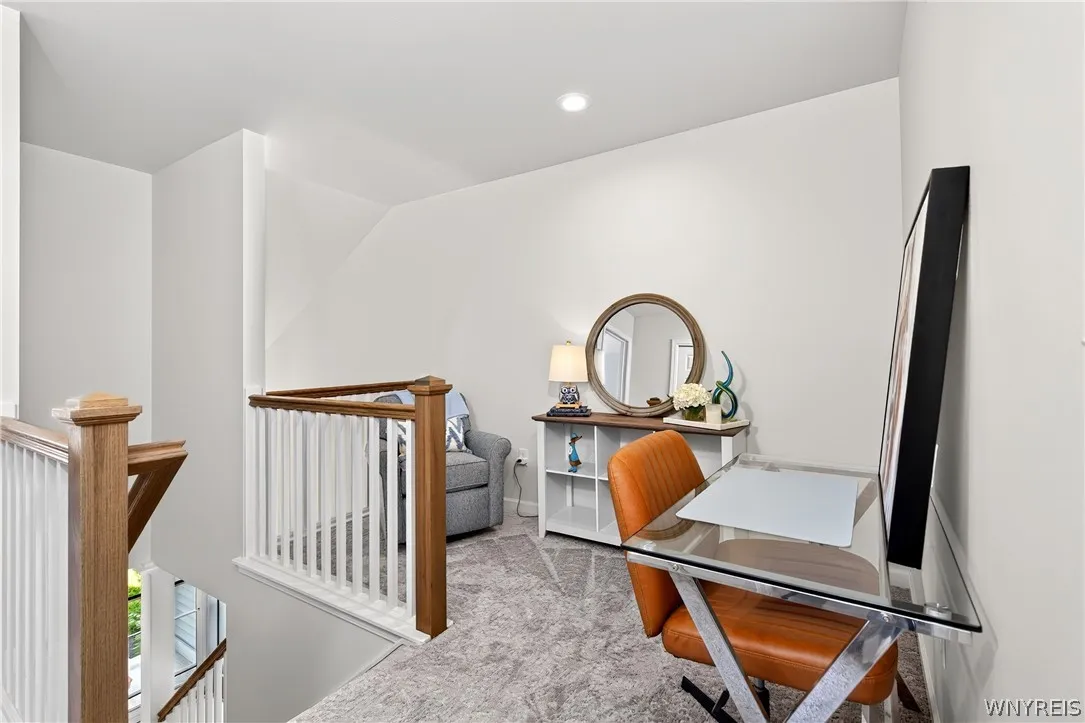 An open upstairs landing features carpeted flooring and wooden railings overlooking the staircase.