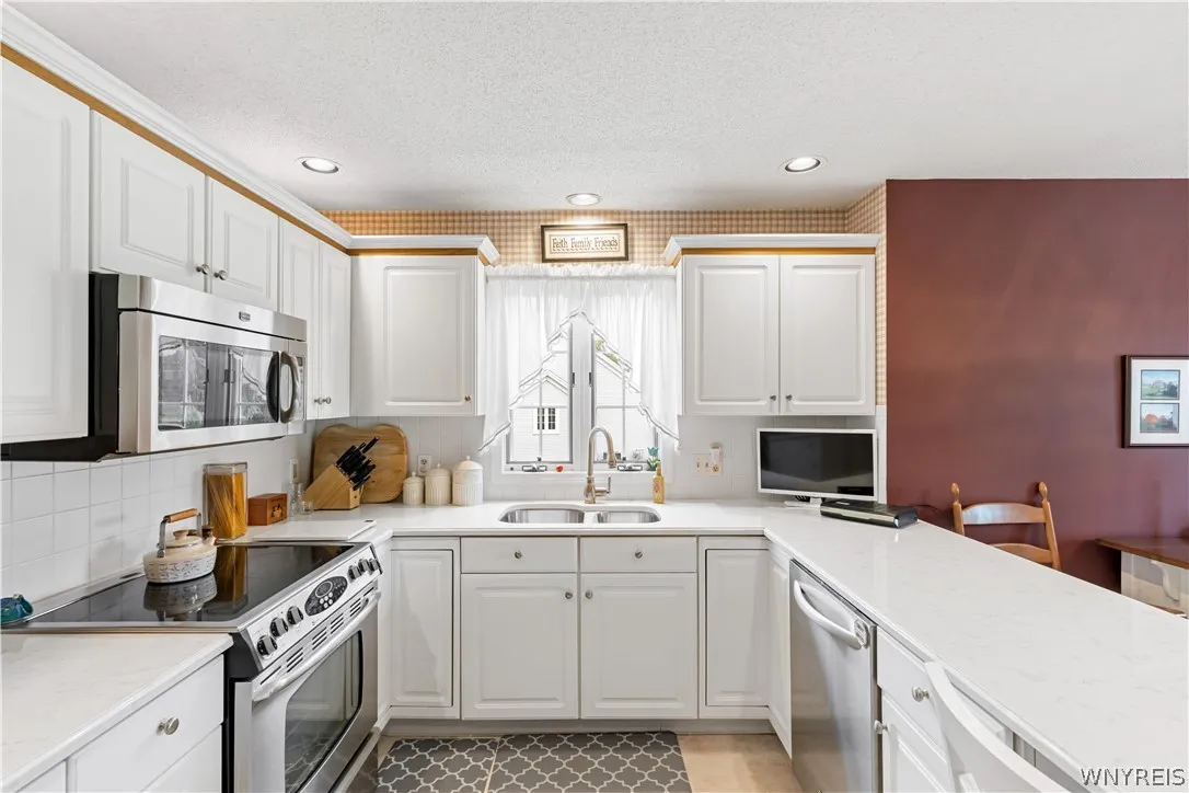 Crisp white cabinetry paired with modern stainless steel appliances creates an efficient, inviting workspace.