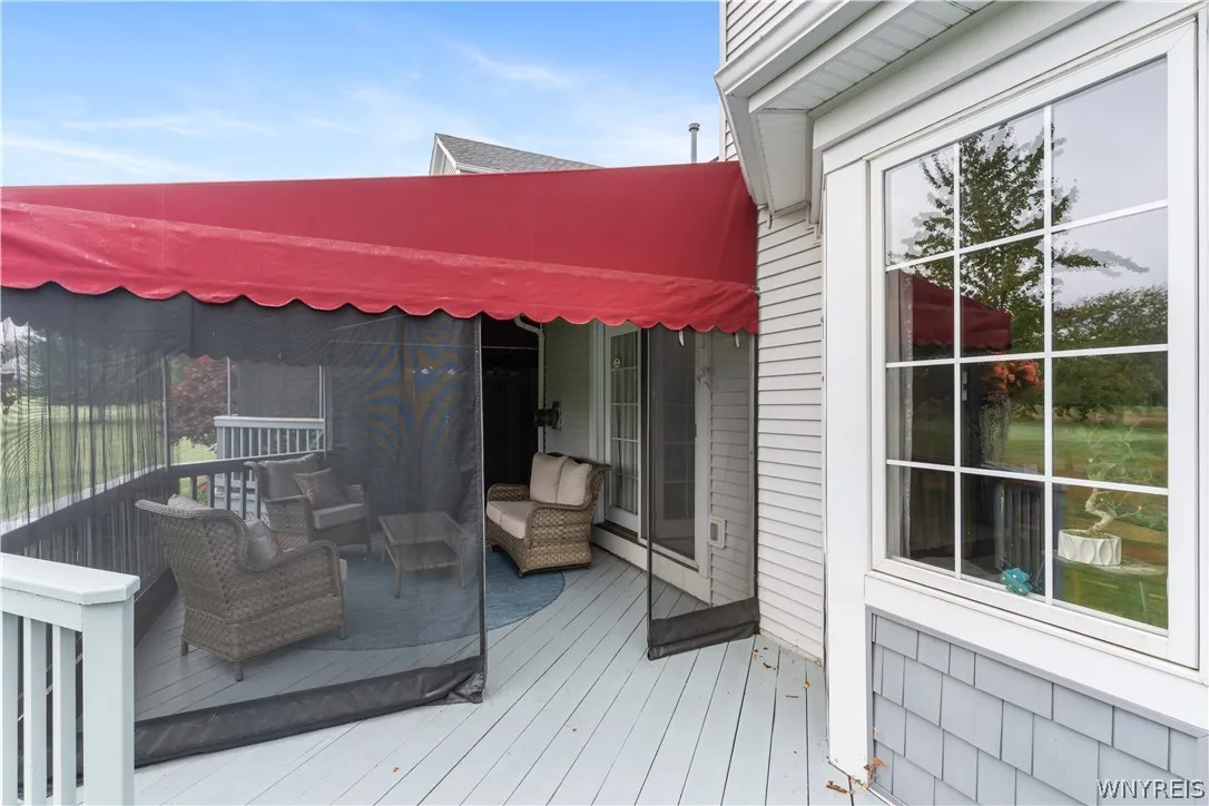 An expansive outdoor deck features a screened-in seating area sheltered by a red canopy.