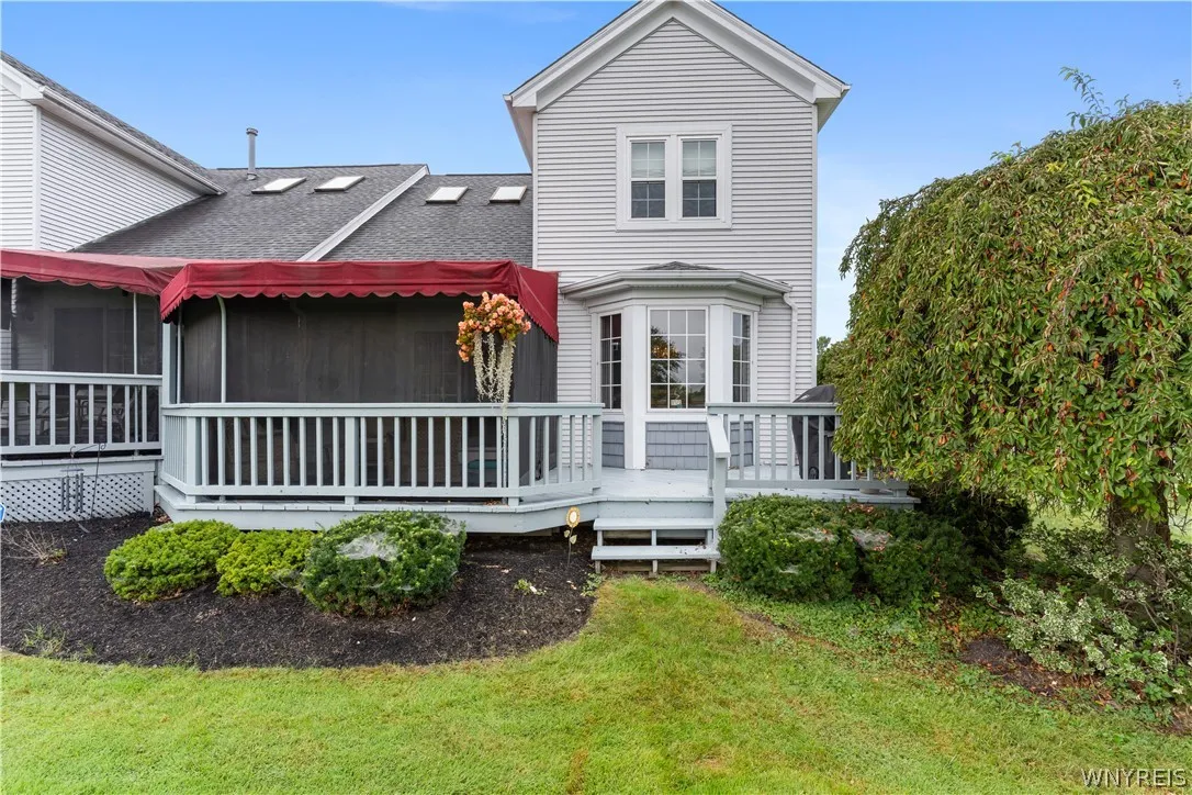 An elevated wood deck with custom awnings extends from the vinyl-sided rear exterior.
