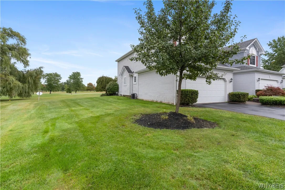 A spacious green lawn borders the side of this multi-level home with an attached garage.
