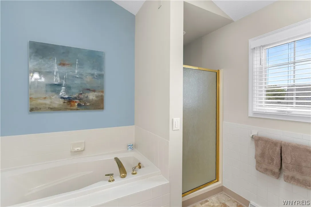 Vaulted ceilings soar over a separate soaking tub and walk-in shower layout.