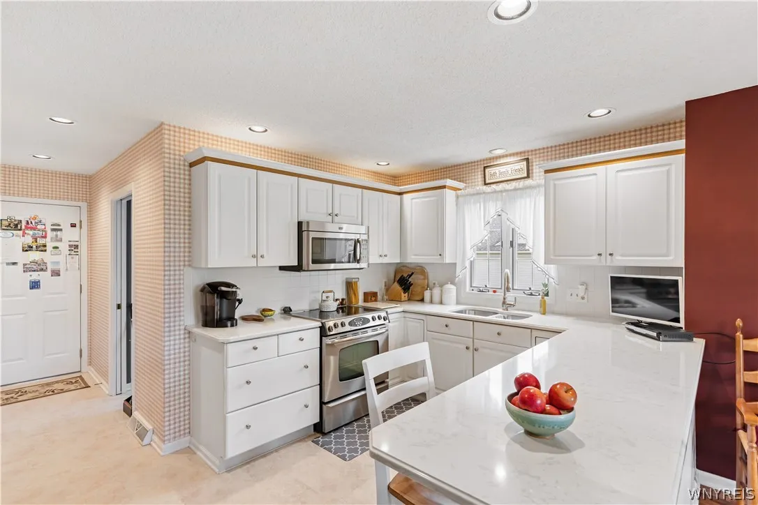 White cabinetry, stone counters, and a raised breakfast bar create a highly functional kitchen workspace.
