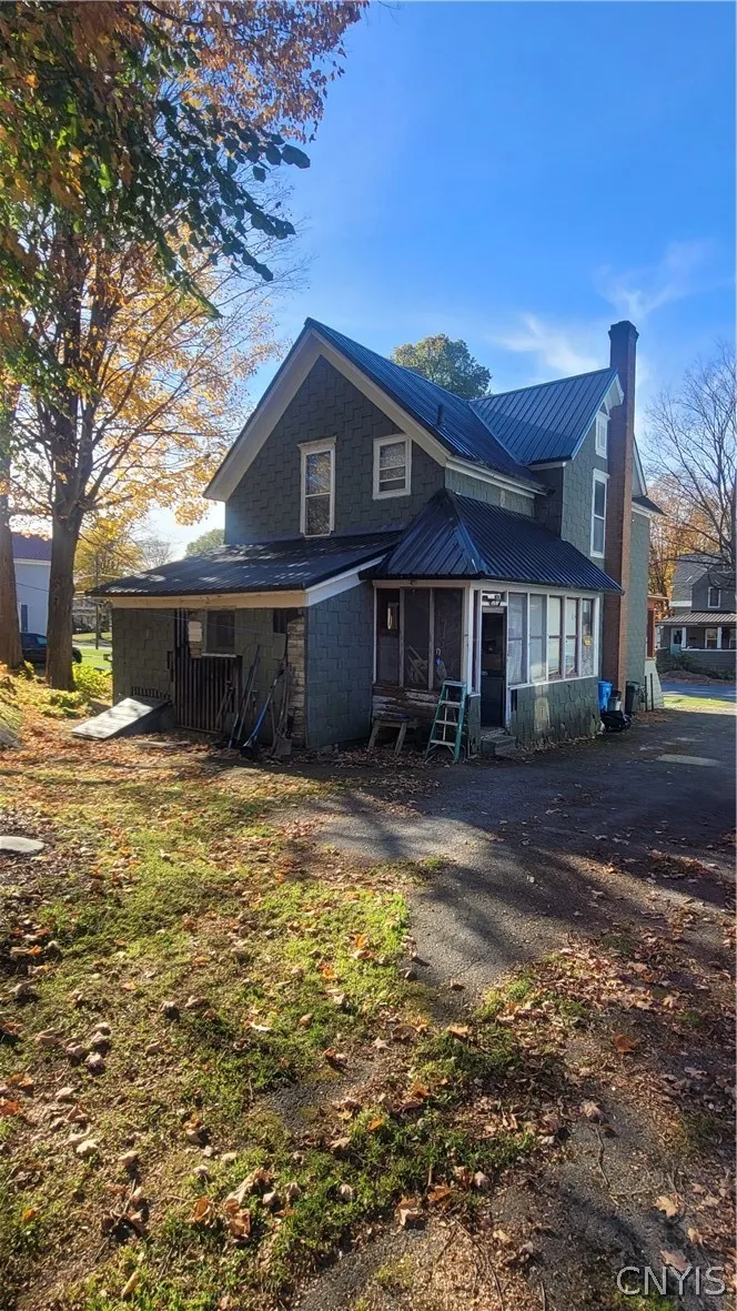 Back of house view showing newer metal roofing on hal of structure