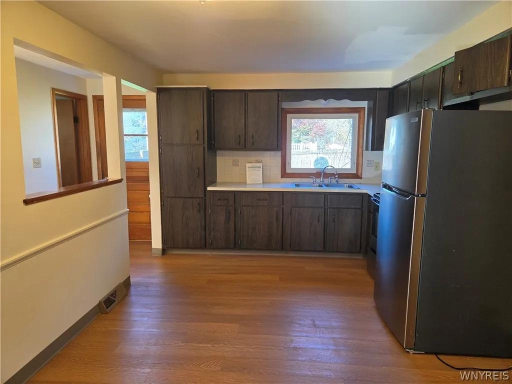 Large eat-in kitchen with new flooring stainless appliances on left side and dual stainless sink, right side has white appliances
