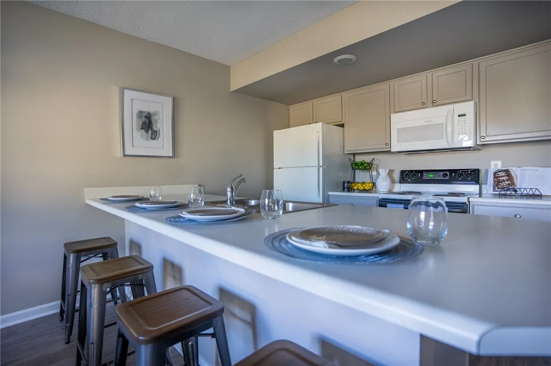 View of typical kitchen in the open plan layout showing breakfast bar. Kitchens include dishwasher, refrigerator, microwave, garbage disposal, and stove/oven.