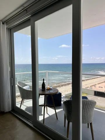 The floor to ceiling sliding doors open to the ocean's beautiful turquise blue hues and the sound of waves lapping at the shore.